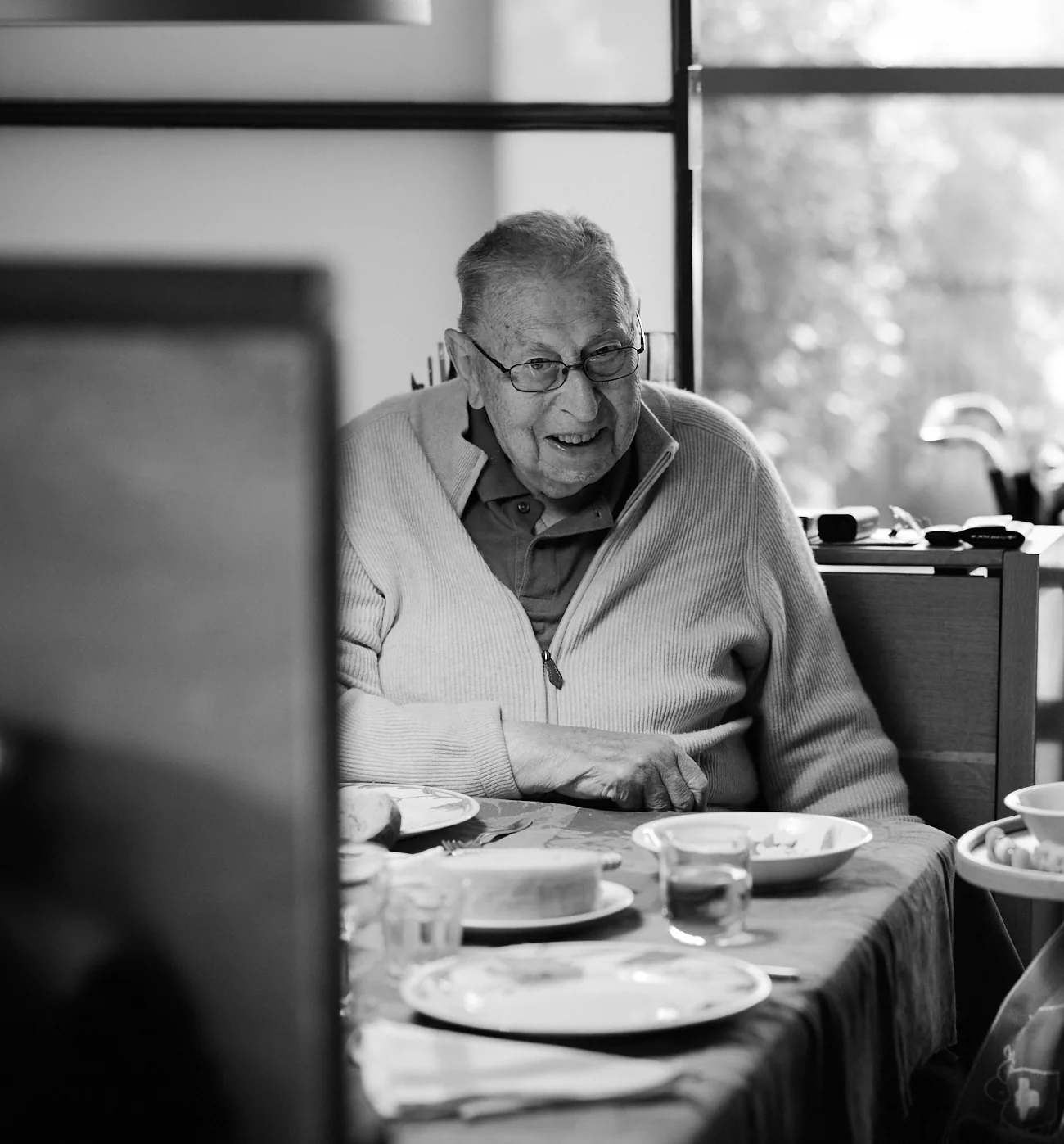 Il nonno, sorridente a tavola, in bianco e nero